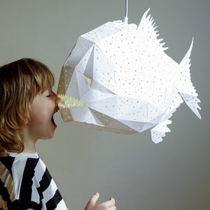 A young boy is playing with a Nautical Hanging Light Glowfish in a ocean-themed kids' room.