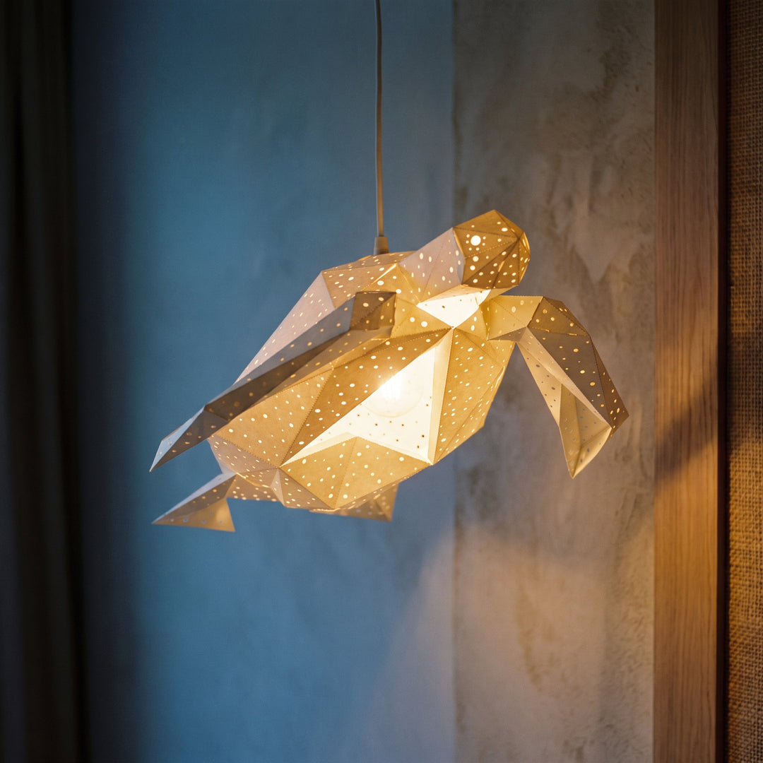 A lit White Baby Sea Turtle Pendant Light against a blue wall