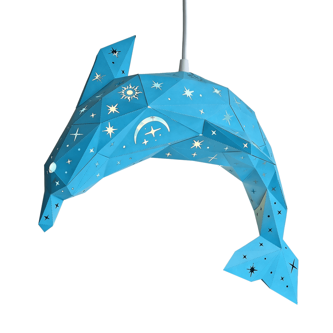 A blue dolphin-shaped hanging lamp made of faceted geometric panels, decorated with white stars, moons, and sun motifs, suspended against a white background.