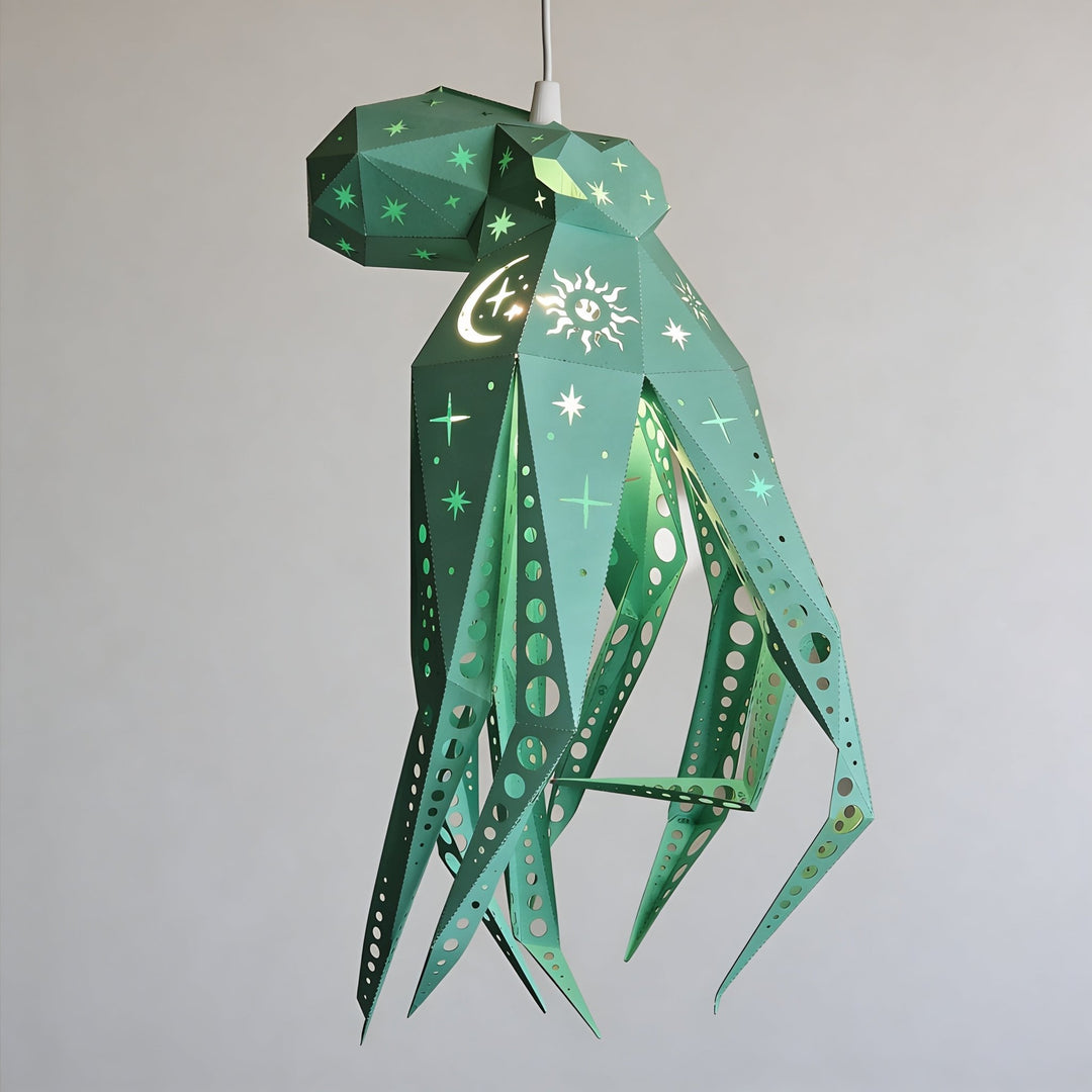 A green geometric octopus-shaped hanging pendant light made of paper with star, moon, and sun motifs, suspended against a plain light gray wall.