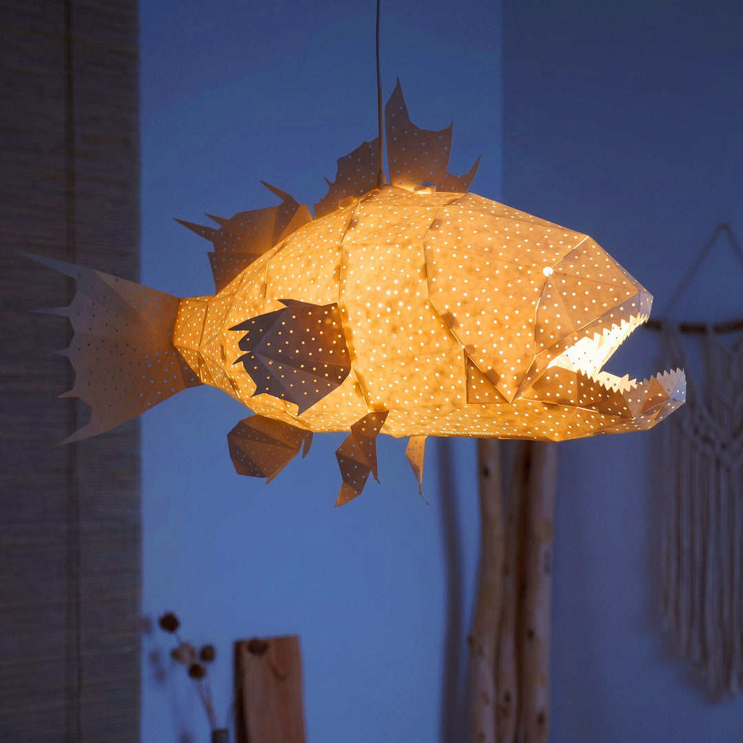 A lit White Lapu Lapu Origami Fish Pendant Light in a dim blue room