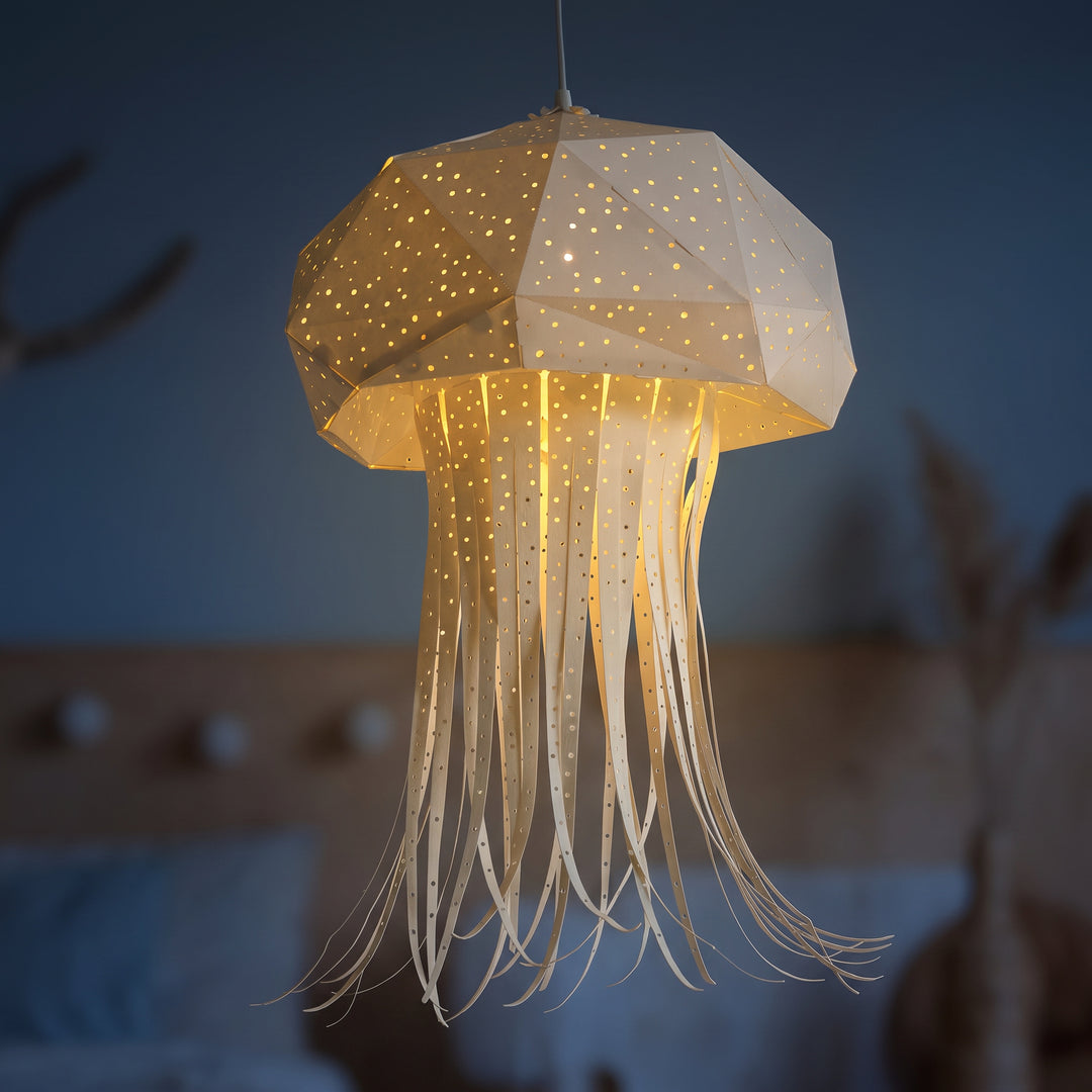 A lit White Origami Jellyfish Hanging Light in a dim blue room