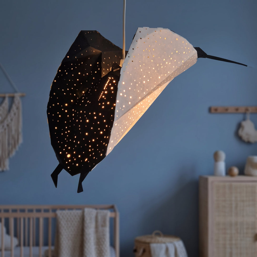 A lit Black-White Ray Origami Pendant Light in a blue nursery