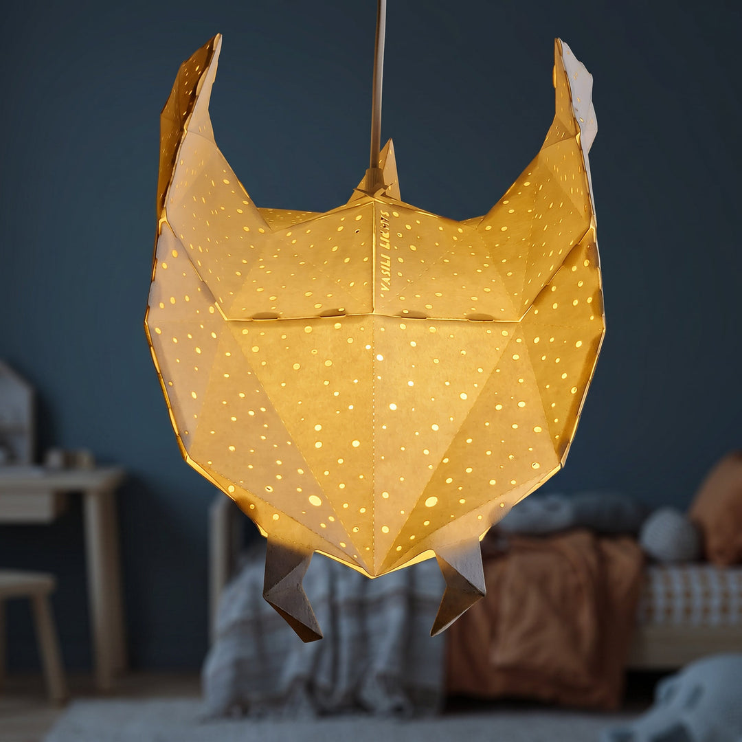 A lit White Ray Origami Pendant Light glowing warm yellow in a blue nursery
