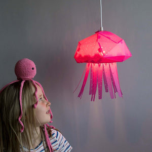 A little girl looks at hanging Baby Jelly Lamp for Nursery and dives into calming seas of of her magination.
