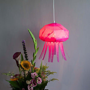 A shaped as a jellyfish, Baby Jellyf Lamp for Nursery hanging above a vase of flowers.