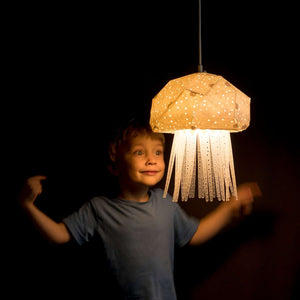 A young boy is looking with admiration at the Jelly Lamp hanging in his Nursery or Bedroom.