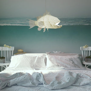 A bedroom with a fish-shaped Nautical Ceiling Lamp hanging above a bed near the wall covered by a ocean-themed wallpaper.