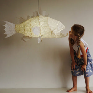 A little girl gazes up with pure delight at a Nautical Ceiling Lamp of white color.