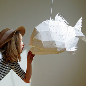 A cute girl in a girl in a straw hat is playng with a Nautical Hanging Light Glowfish in a kids' room.