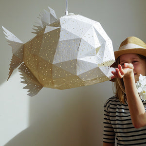 A cute girl girl in a straw hat is playng with a Nautical Hanging Light Glowfish in a kids' room.