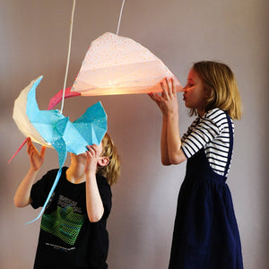 Two children playing with manta-ray-inspired Ray Origami Lamps from Vasili Lights.